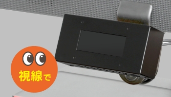ディスプレイの下に取り付けられた黒い小型の視線検知センサー機器。写真左側に目のアイコンと『視線で』という説明が表示され、視線による操作が可能であることを示している